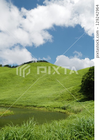 A natural landscape with green hills and a small pond shining in the early summer sunlight A natural landscape with green hills and a small pond shining in the early summer sunlight 129242964