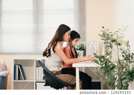 Parent and child engaged in online language learning together at home Parent and child engaged in online language learning together at home 129243333