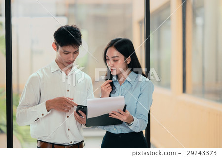 Two businesspeople discussing project details, reviewing documents and data in an office Two businesspeople discussing project details, reviewing documents and data in an office 129243373