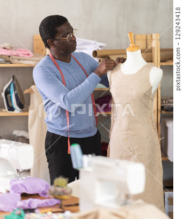 Dressmaker constructing custom dress on mannequin in sewing workshop Dressmaker constructing custom dress on mannequin in sewing workshop 129243418