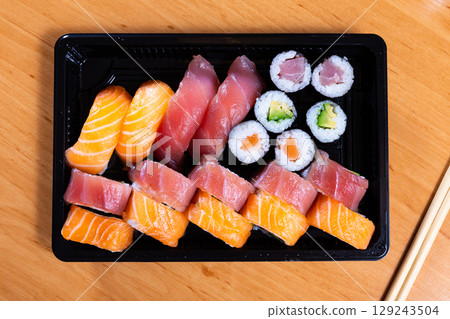 Set of nigiri sushi, uramaki and norimaki rolls in plastic tray 129243504