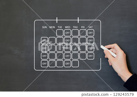 A person drawing a calendar on a blackboard that reflects a three-day work week 129243579
