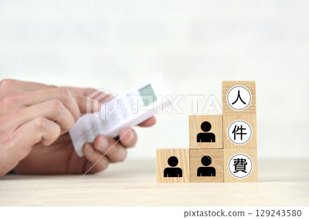 Manager's hand calculating labor costs with a calculator 129243580