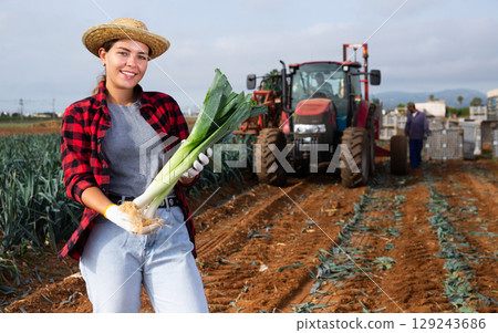 Portrait of positive girl farmer with crate of fresh leek 129243686
