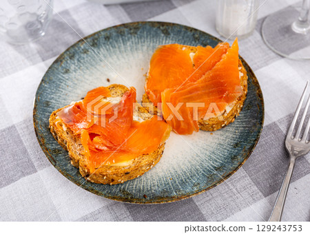 Two delicious smoked salmon sandwiches served on plate 129243753