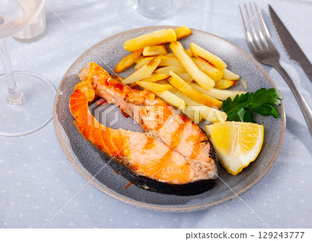 Delicious spanish dish, grilled salmon with fries potatoes served with lemon and parsley 129243777
