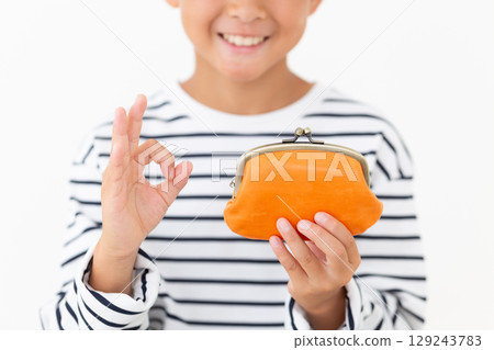 An elementary school boy making a circle sign while holding an orange clasp wallet 129243783