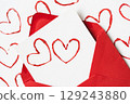 Handmade Valentine's Day card with red printed heart stamps in red envelope on white background. 129243880
