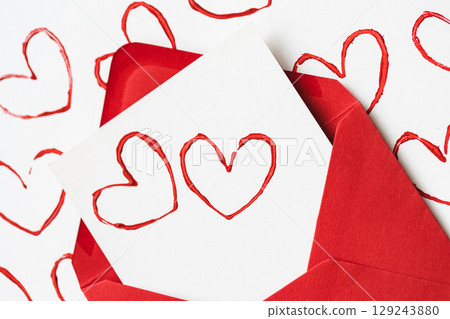 Handmade Valentine's Day card with red printed heart stamps in red envelope on white background. Handmade Valentine's Day card with red printed heart stamps in red envelope on white background. 129243880