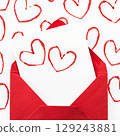 Handmade Valentine's Day card with red printed heart stamps in red envelope on white background. 129243881