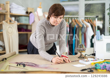 Woman tailor draw dress pattern of product on paper 129243886