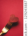 Valentine's day greeting card in minimal style with shiny heart pierced by golden fork on red background. 129243887