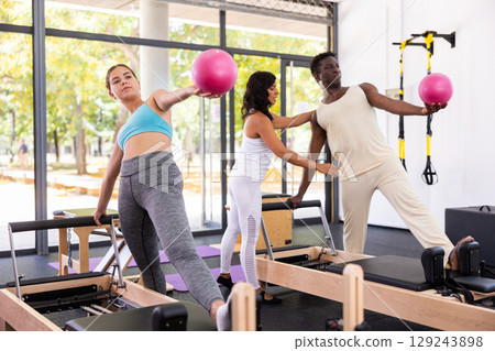 Positive woman and man maintaining active lifestyle exercising with small pilates ball Positive woman and man maintaining active lifestyle exercising with small pilates ball 129243898