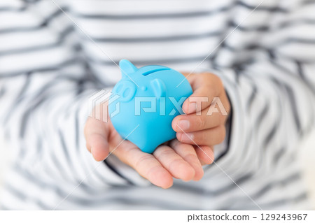Elementary school boy holding a blue piggy bank 129243967