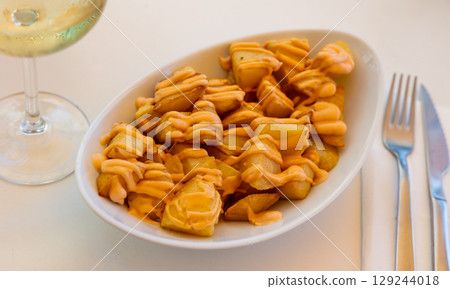 Baked potatoes Patatas bravas with spicy creamy sauce aioli 129244018