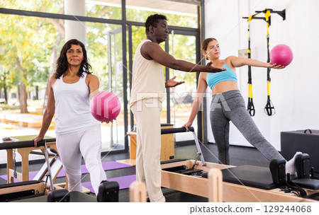 Man and woman exercising with ball at pilates lesson Man and woman exercising with ball at pilates lesson 129244068