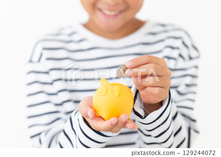 小學男孩把錢放進黃色存錢筒 小學男孩把錢放進黃色存錢筒 129244072