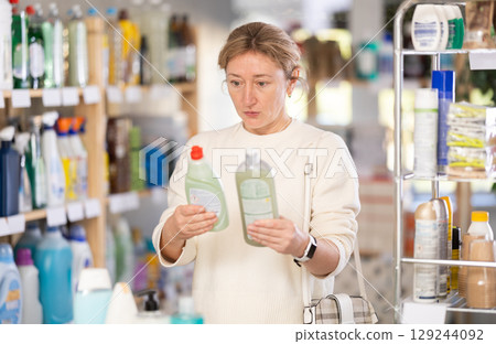 Adult woman chooses dishwashing detergent in store 129244092