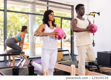Female trainer controlling movements of woman and man doing pilates 129244136