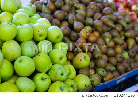 Ripe juicy green pears and apples in box on counter at supermarket Ripe juicy green pears and apples in box on counter at supermarket 129244150