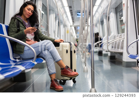 Woman passenger using phone in subway car Woman passenger using phone in subway car 129244393