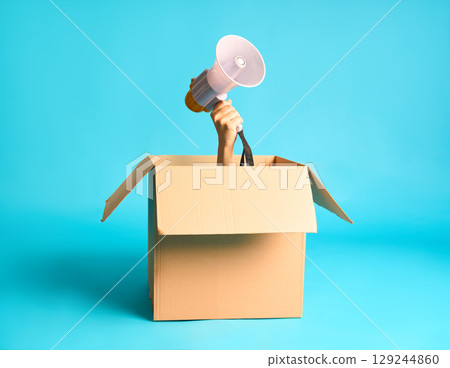 Hand with megaphone raised from cardboard box 129244860