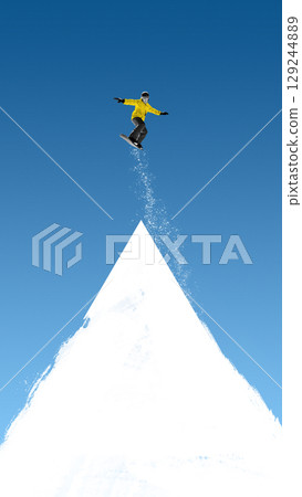 Creative collage of male snowboarder in yellow jacket floating over white triangular peak 129244889