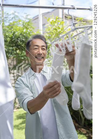 A man in his 60s hanging out laundry 129245226