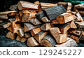 Stacked firewood logs with rough textures and natural wood tones for outdoor or rustic settings 129245227