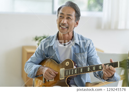 一名 60 多歲的男子正在彈奏電吉他 一名 60 多歲的男子正在彈奏電吉他 129245576