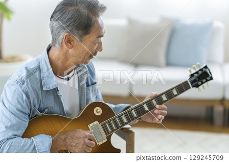 Profile of a man in his 60s playing an electric guitar 129245709