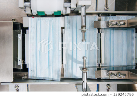 Face mask, Surgical mask production line, Closeup machine conveyor belt roller in hygiene factory Face mask, Surgical mask production line, Closeup machine conveyor belt roller in hygiene factory 129245796