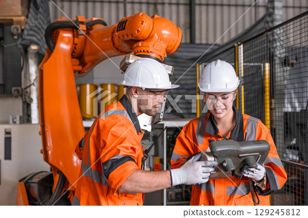 Robotic technician engineer male training helping young women team control operate robot welding arm 129245812