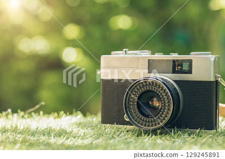 closeup vintage classic compact film camera at green outdoor with copy space for text 129245891