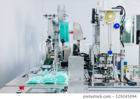 Face mask, Surgical mask production line, Closeup machine conveyor belt roller in hygiene factory Face mask, Surgical mask production line, Closeup machine conveyor belt roller in hygiene factory 129245894