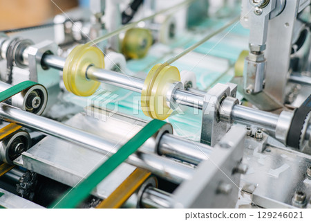 Face mask, Surgical mask production line, Closeup machine conveyor belt roller in hygiene factory 129246021