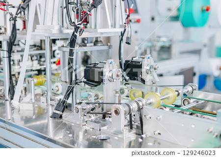 Face mask, Surgical mask production line, Closeup machine conveyor belt roller in hygiene factory Face mask, Surgical mask production line, Closeup machine conveyor belt roller in hygiene factory 129246023