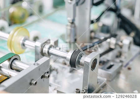 Face mask, Surgical mask production line, Closeup machine conveyor belt roller in hygiene factory 129246028