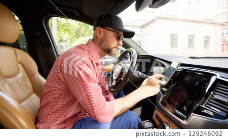 Man using smartphone inside a car while sitting on driver's seat Man using smartphone inside a car while sitting on driver's seat 129246092