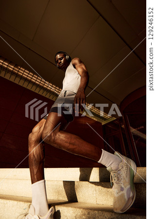 Athletic man in workout gear ascending stairs during an outdoor training session Athletic man in workout gear ascending stairs during an outdoor training session 129246152