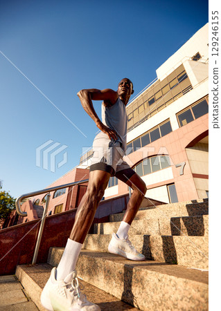 Athletic man exercising on steps outdoors during daytime for fitness and wellness 129246155