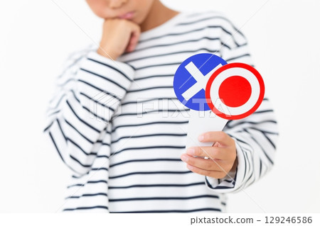 An elementary school boy holding a plate with a circle and an X and worrying An elementary school boy holding a plate with a circle and an X and worrying 129246586