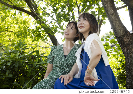 Two women relaxing in the park 129246745