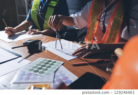 Closeup of team of industrial engineers meeting analyze machinery blueprints consult project on table in manufacturing factory. Working in manufacturing plant or production plant. Closeup of team of industrial engineers meeting analyze machinery blueprints consult project on table in manufacturing factory. Working in manufacturing plant or production plant. 129246861
