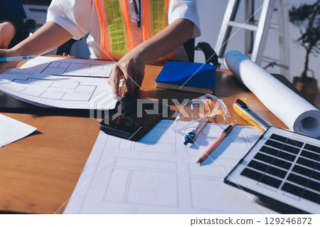 Closeup of team of industrial engineers meeting analyze machinery blueprints consult project on table in manufacturing factory. Working in manufacturing plant or production plant. Closeup of team of industrial engineers meeting analyze machinery blueprints consult project on table in manufacturing factory. Working in manufacturing plant or production plant. 129246872