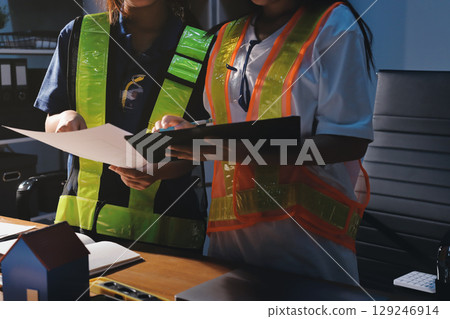 Closeup of team of industrial engineers meeting analyze machinery blueprints consult project on table in manufacturing factory. Working in manufacturing plant or production plant. Closeup of team of industrial engineers meeting analyze machinery blueprints consult project on table in manufacturing factory. Working in manufacturing plant or production plant. 129246914