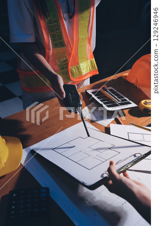 Closeup of team of industrial engineers meeting analyze machinery blueprints consult project on table in manufacturing factory. Working in manufacturing plant or production plant. 129246946