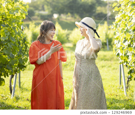 Two women walking through a vineyard 129246969