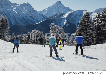 Snowboarders and skiers ski in the resort on the slopes Snowboarders and skiers ski in the resort on the slopes 129247125
