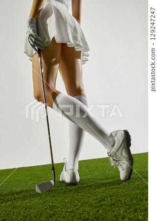 Rear view of female golfer standing with iron club 129247247